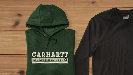 Due maglioni Carhartt poggiano su una base di legno.